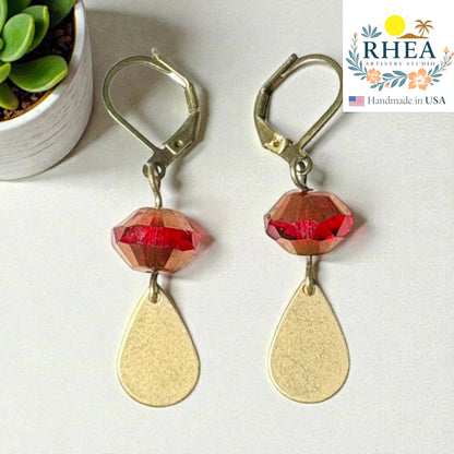 Rhea Artistry Studio handcrafted drop earrings with faceted red glass beads and brushed brass teardrop charms, 2 inches long.