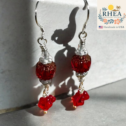 Rhea Artistry Studio red glass bead drop earrings with silver-toned detailing and star charms, 1.75 inches long.