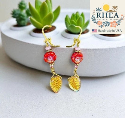Rhea Artistry Studio red hibiscus floral bead drop earrings with pink and gold leaf details.