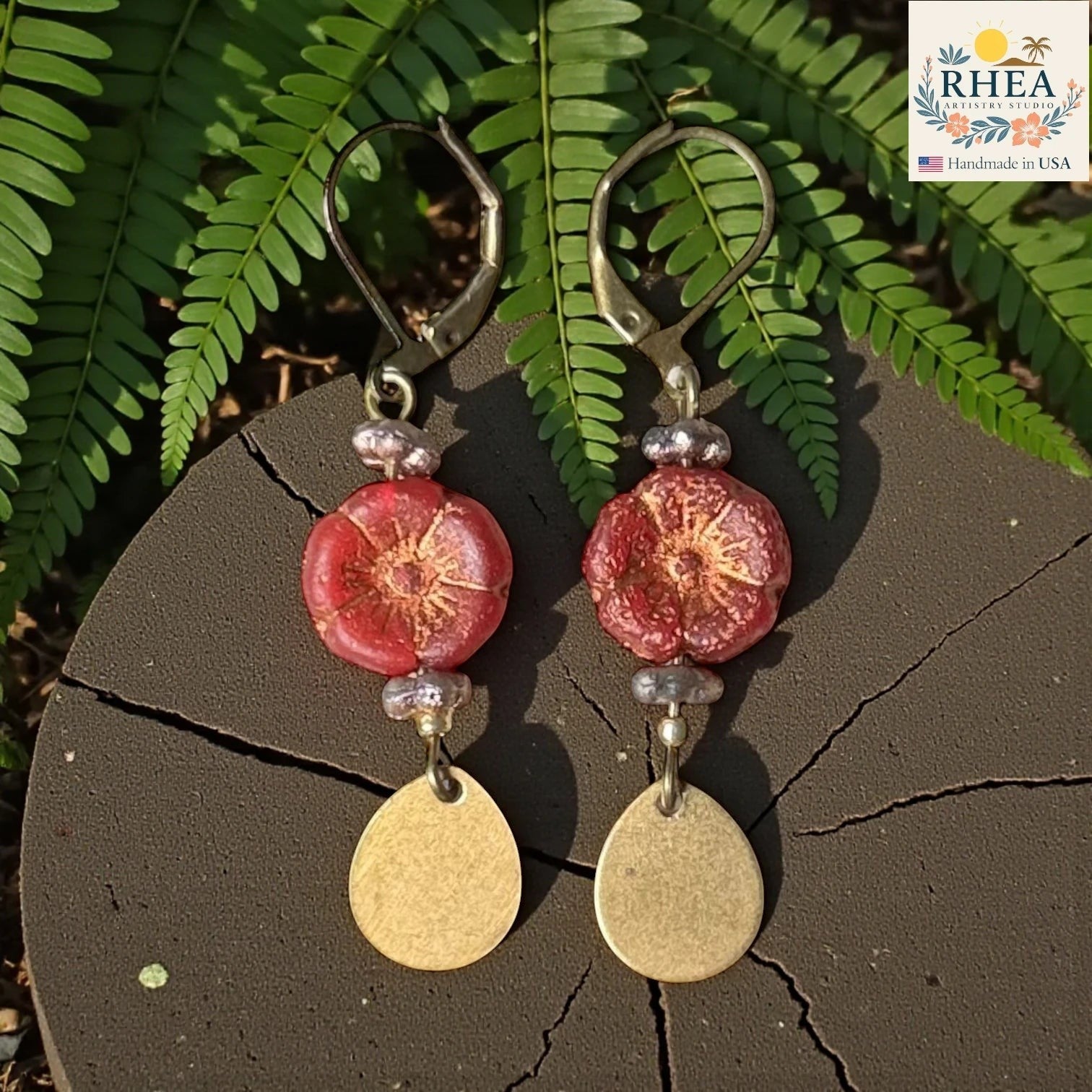 Rhea Artistry Studio red hibiscus glass bead drop earrings with brass teardrop charms and leverback hooks.