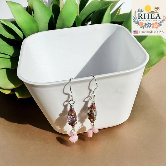 Rhea Artistry Studio rosé pink Czech glass earrings with star accents and silver-plated French hooks, approx. 1.75 inches long.