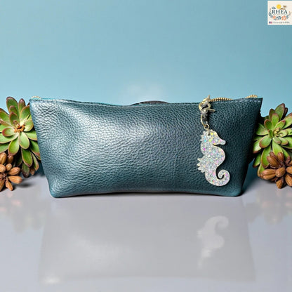 Rhea Artistry Studio holographic seahorse acrylic charm with brass clasp attached to a teal pebbled leather pouch.