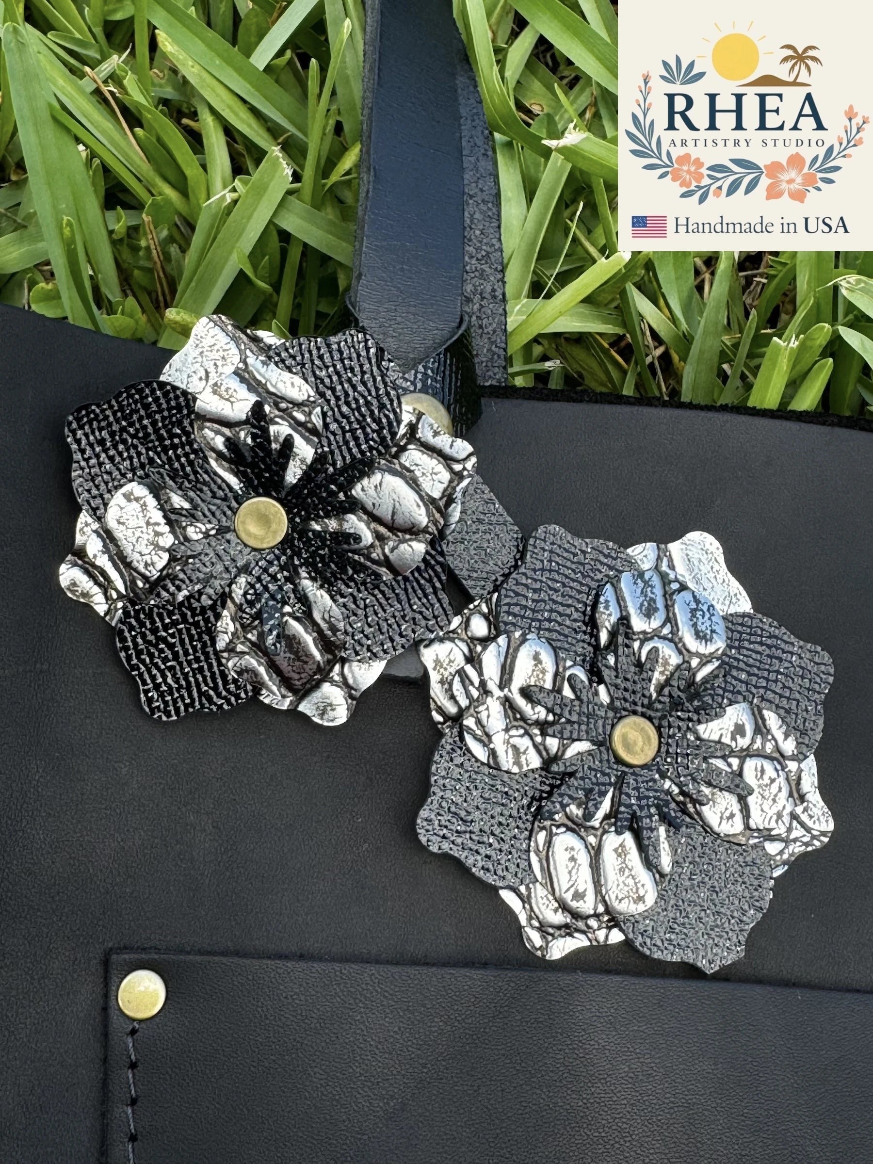 Rhea Artistry Studio double leather flower charm in silver and black, featuring textured full-grain leather petals and brass rivets.