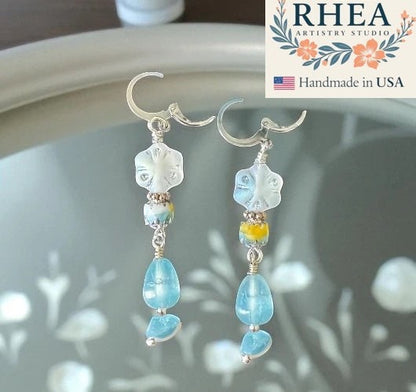 Rhea Artistry Studio handmade silver drop earrings with white floral beads, blue gemstones, and yellow accents.