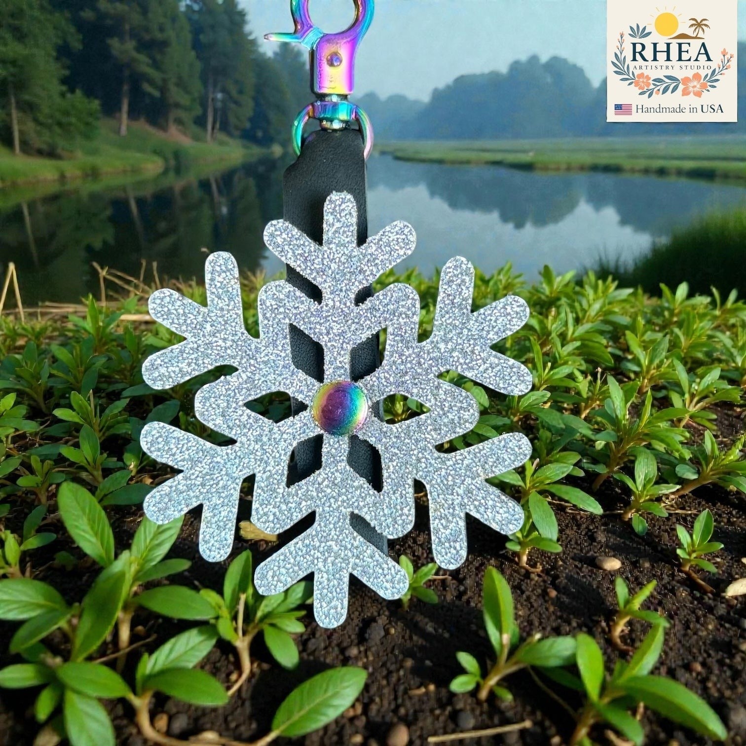 Rhea Artistry Studio silver glitter snowflake leather charm with rainbow center detail and rainbow clasp.