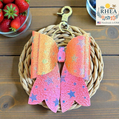 Rhea Artistry Studio handmade pink and orange star bow bag charm with brass hardware.