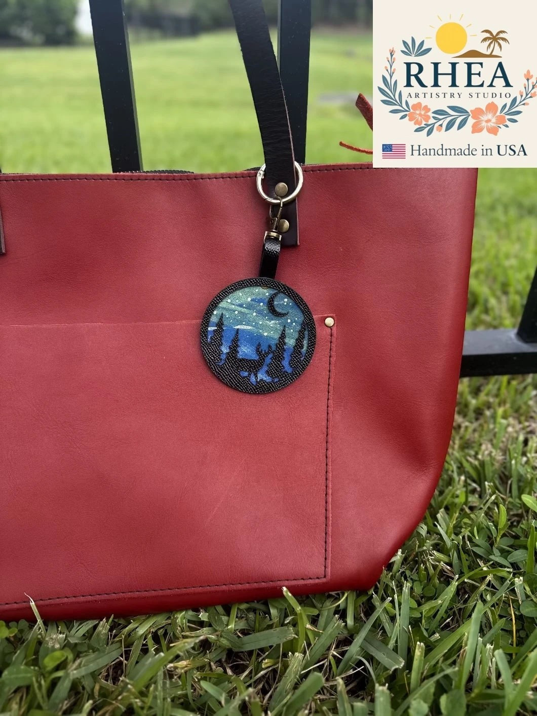 Rhea Artistry Studio hand-painted leather bag charm featuring a starry night scene with a deer and forest silhouette on vegetable-tanned leather.