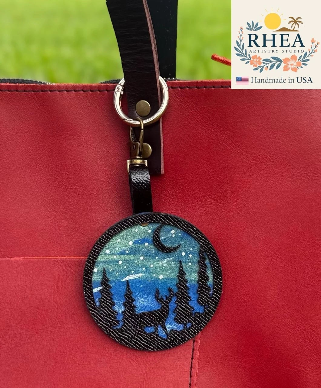 Rhea Artistry Studio hand-painted leather bag charm featuring a starry night sky, moon, pine trees, and a deer silhouette on vegetable-tanned leather.