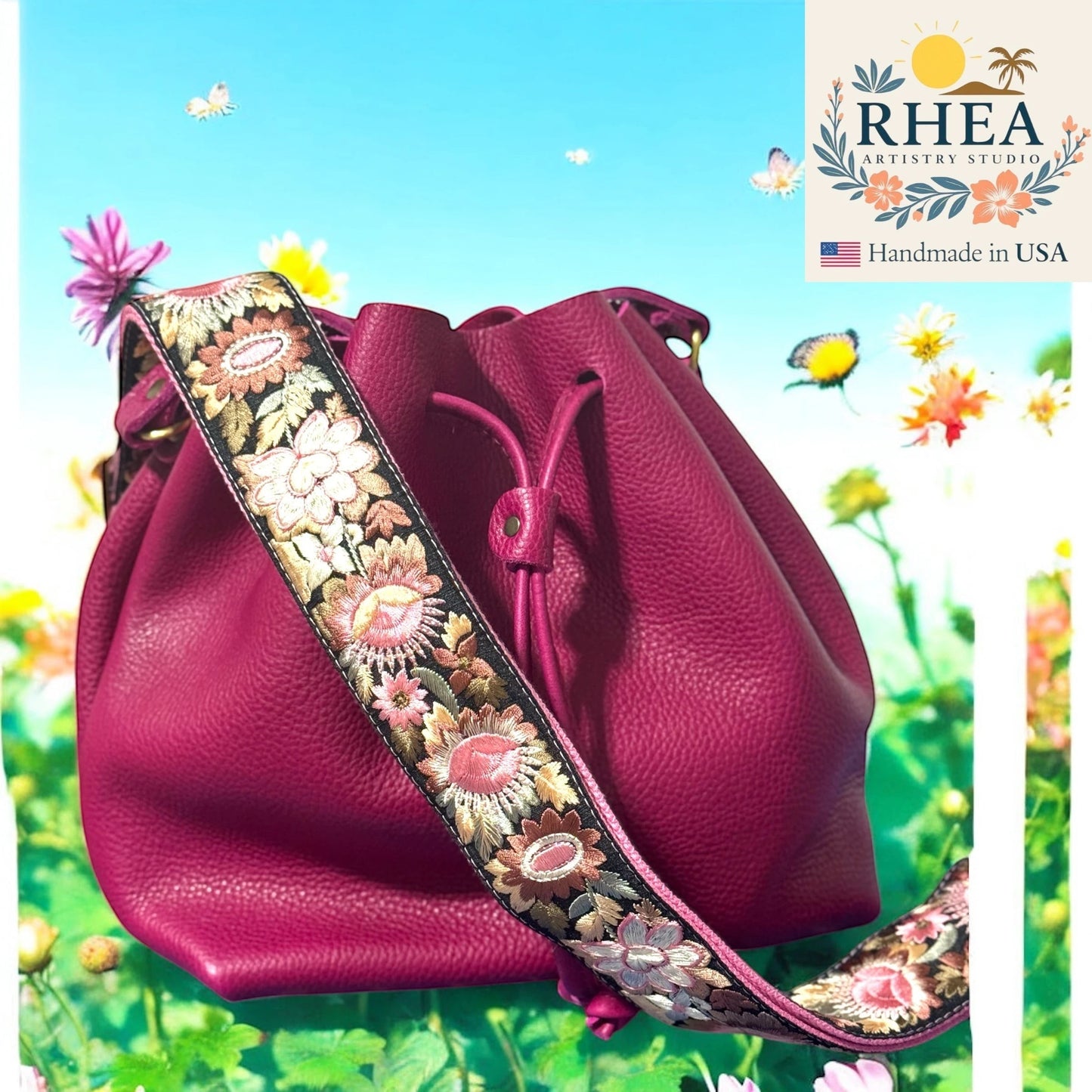 Rhea Artistry Studio 2-inch wide crossbody strap with vibrant floral embroidery in pinks and golds on a black background, attached to a magenta bucket bag.