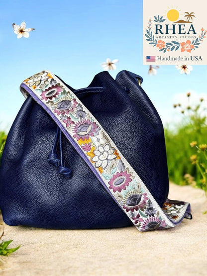 Rhea Artistry Studio navy blue leather bucket bag with a 2-inch wide adjustable sunflower embroidered strap.