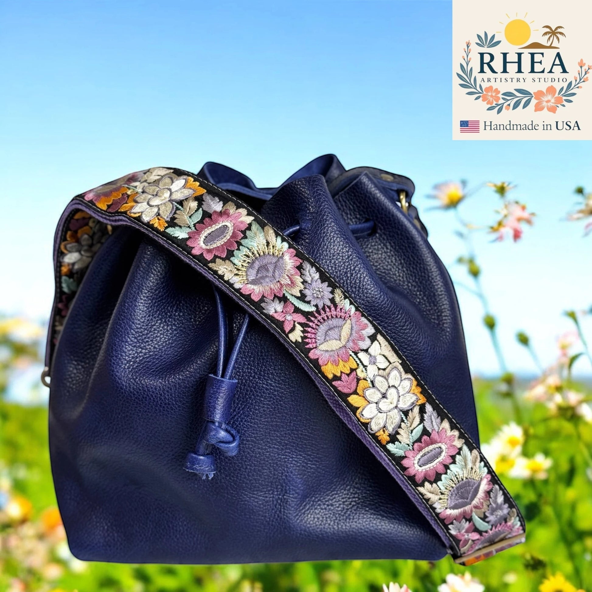 Rhea Artistry Studio navy blue leather bucket bag with a 2-inch wide adjustable sunflower embroidered strap.