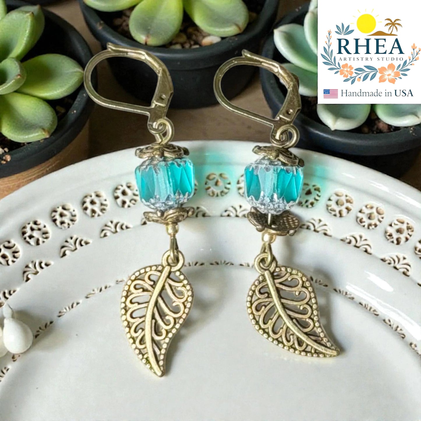 Rhea Artistry Studio antique brass leaf drop earrings with faceted teal glass beads and leverback closures.