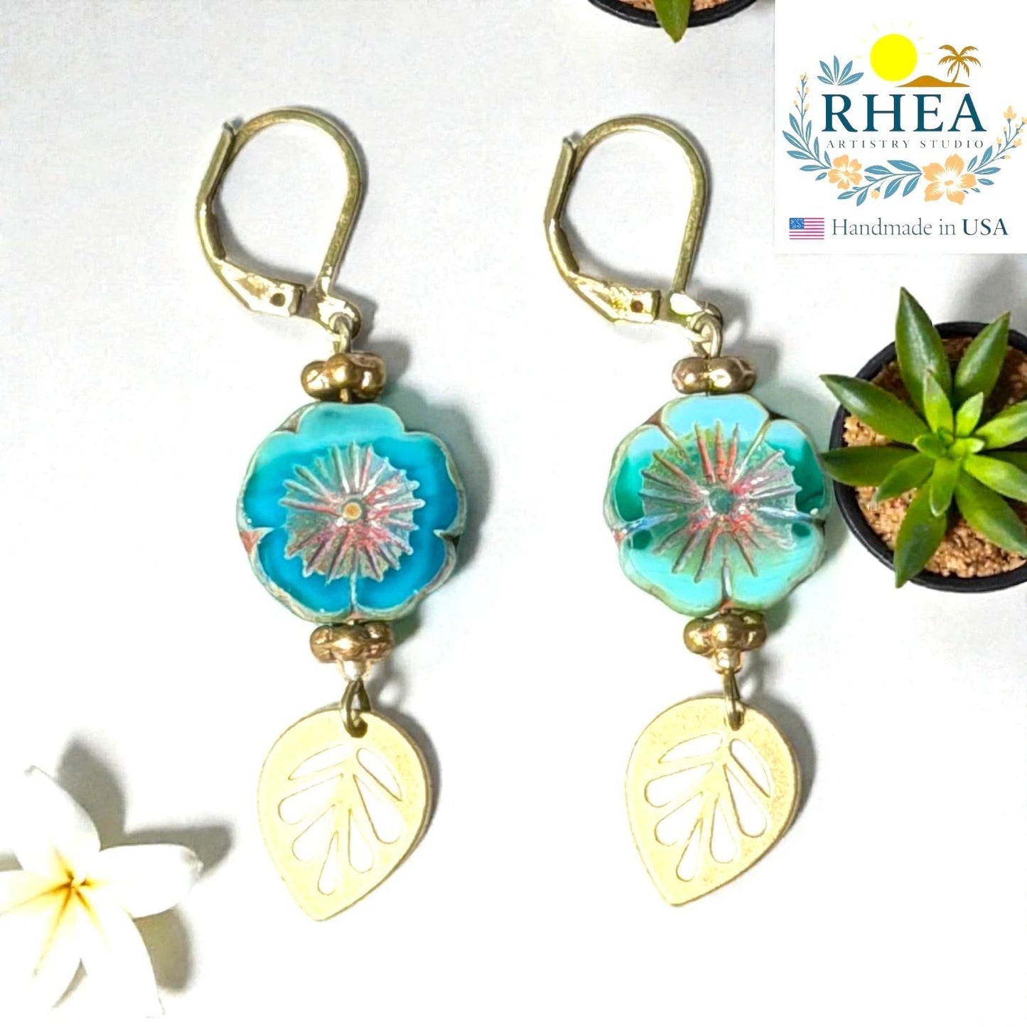 Rhea Artistry Studio handmade turquoise hibiscus glass drop earrings with gold leaf charms and lever back hooks.