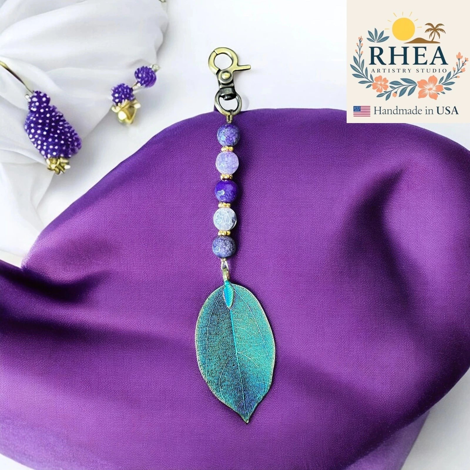 Rhea Artistry Studio handmade violet gemstone bag charm with electroplated natural leaf pendant and gold clasp.