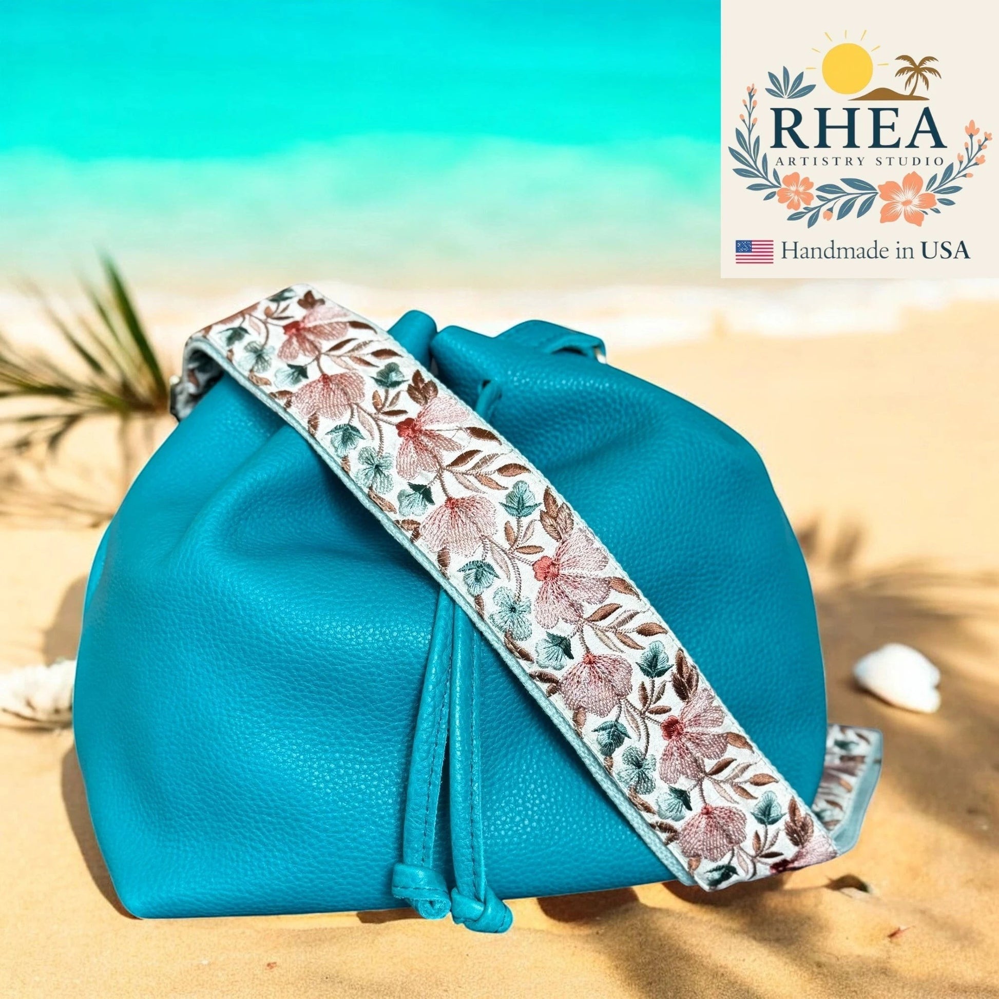 Rhea Artistry Studio 2-inch crossbody strap with wild thistle embroidery on white lace ribbon, adjustable 30-54 inches, with brushed brass hardware.