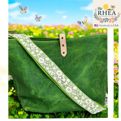 Rhea Artistry Studio green crossbody bag with a 1.5-inch adjustable strap featuring white wildflower embroidery and brushed brass hardware.