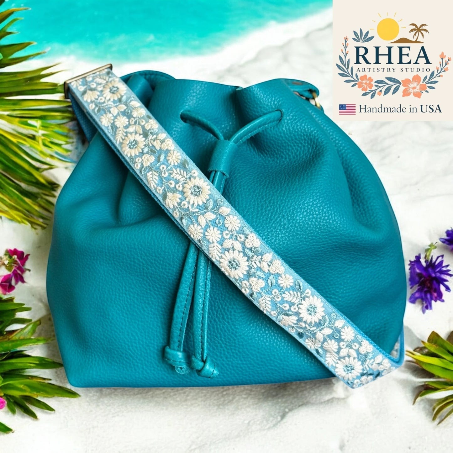 Rhea Artistry Studio 1.5-inch crossbody strap with white wildflower embroidery on blue lace over cotton webbing.