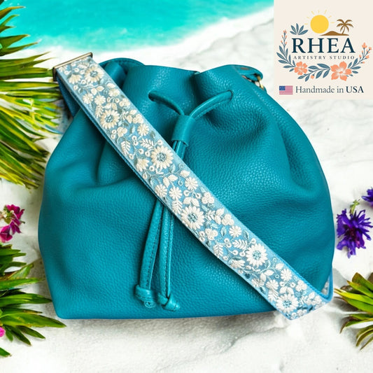Rhea Artistry Studio 1.5-inch crossbody strap with white wildflower embroidery on blue lace over cotton webbing.