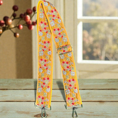 Rhea Artistry Studio yellow crossbody strap with floral embroidery in pink, blue, and red, featuring brushed brass hardware and adjustable length.
