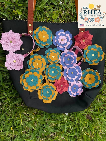 Rhea Artistry Studio yellow and turquoise double leather flower charm with brass rivets and adjustable snap fastener.