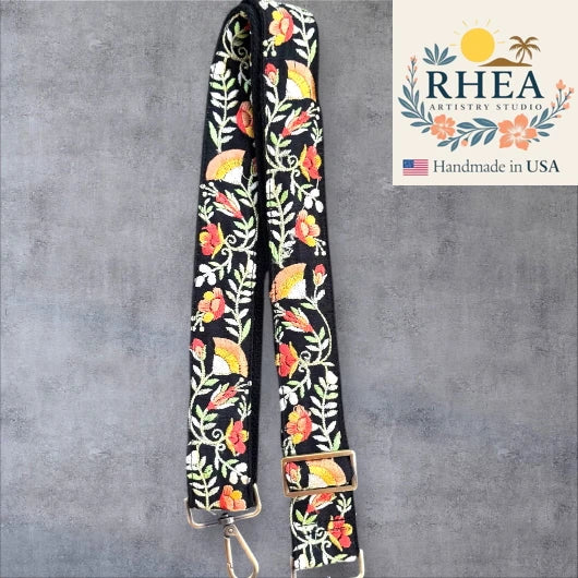 Floral patterned purse strap with RHEA Artistry Studio logo on a gray background