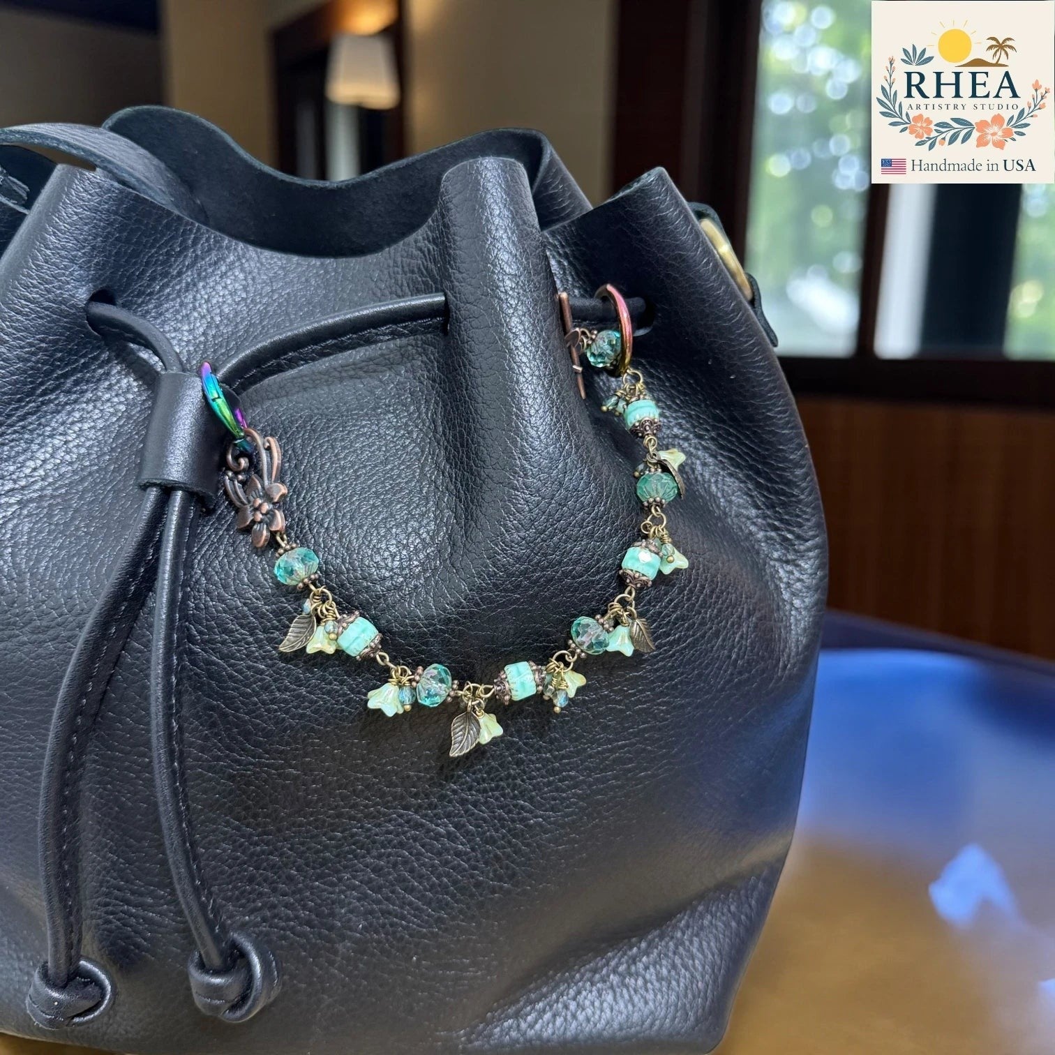 Black leather bag with a decorative purse charm featuring turquoise beads and gold accents.
