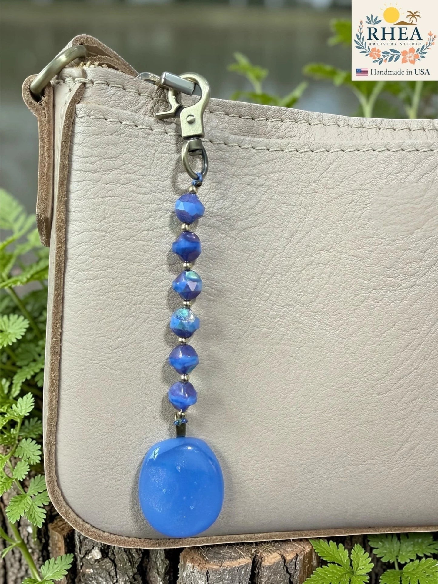 Blue beaded keychain attached to a beige purse with a blurred natural background