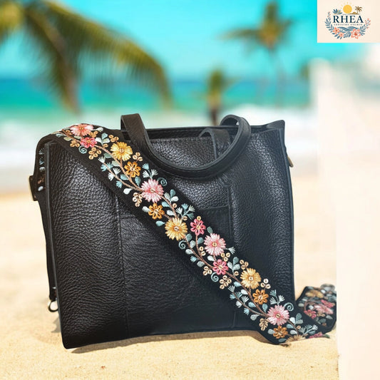 Black handbag with floral strap on a beach