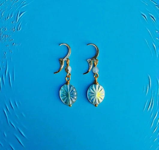 Pair of earrings with circular designs on a blue textured background