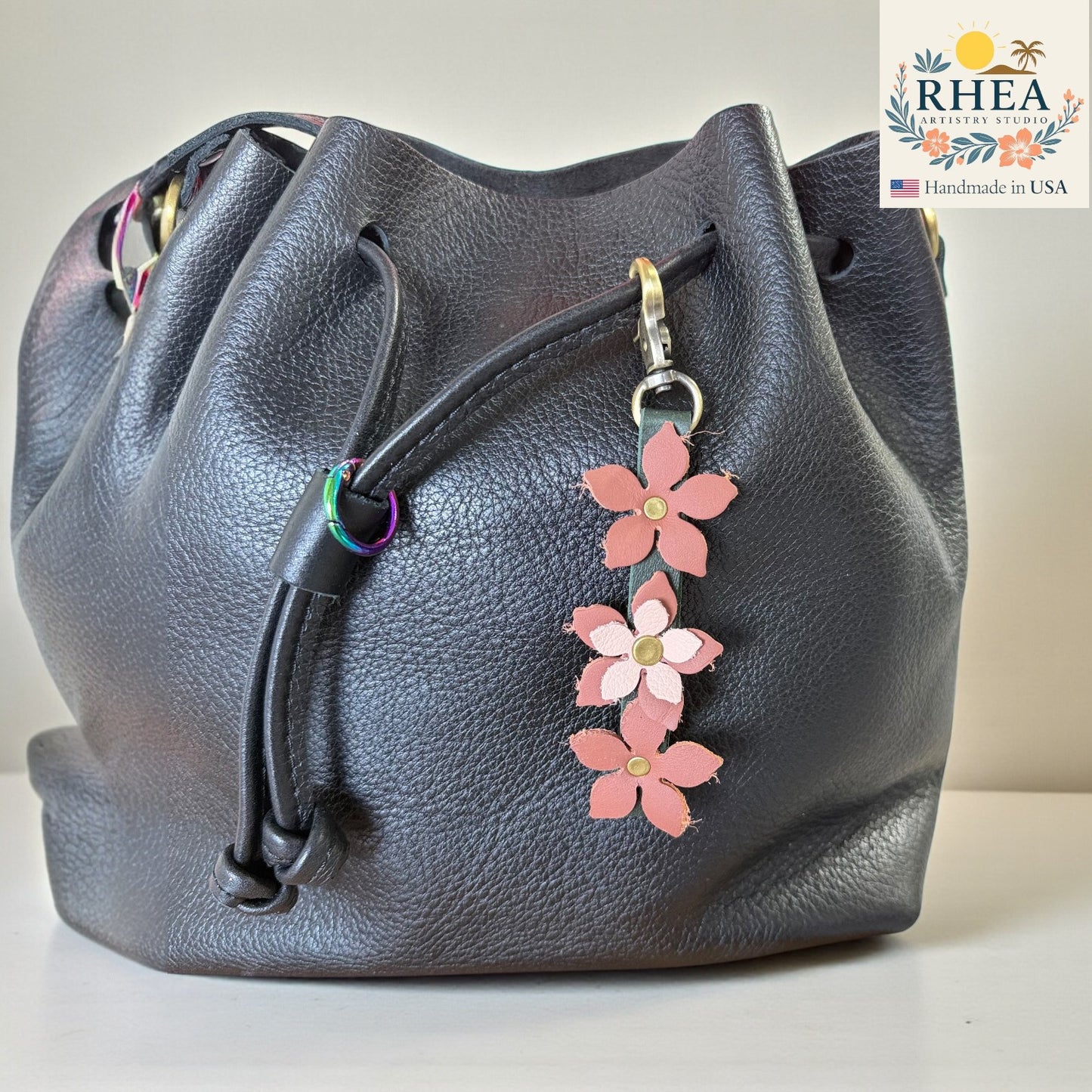 Handmade leather floral charm clipped to a handbag in  pinkish hues