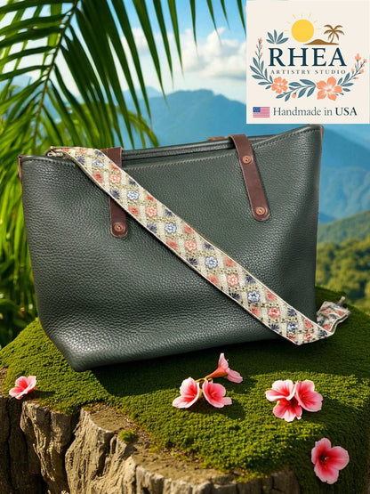 Green handbag with a floral strap on a natural background, featuring the Rhea Artistry Studio logo.