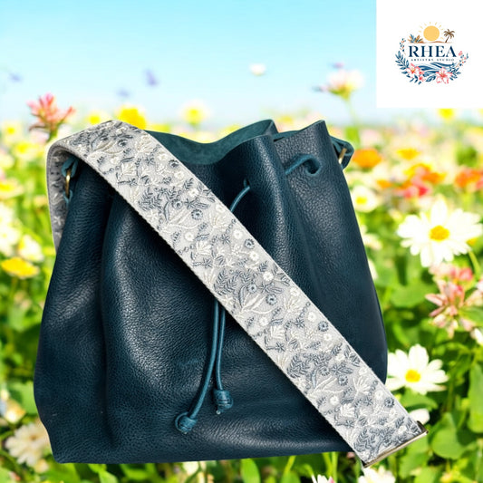 Silverleaf Bloom floral strap on navy leather bucket bag against garden background